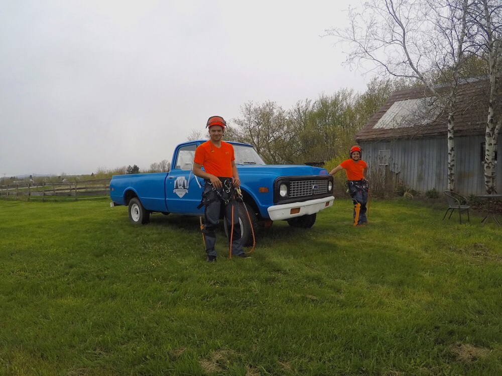 The founders in front of their company truck wearing orange t-shirts.