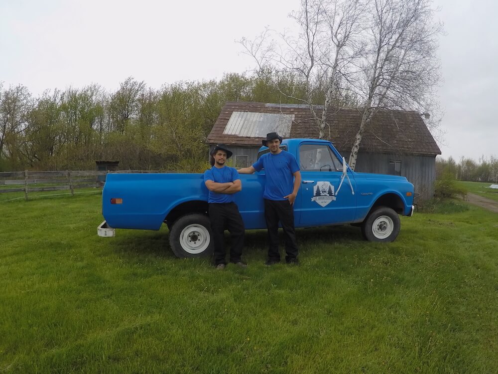 The founders in front of their company truck wearing blue t-shirts.